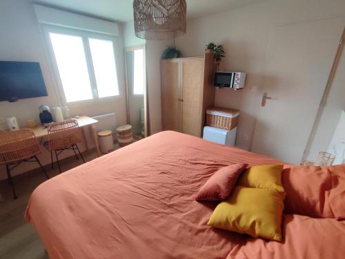 - une chambre avec un lit doté de draps et d'oreillers orange dans l'établissement Hébergement le Cèdre, à Lavaur