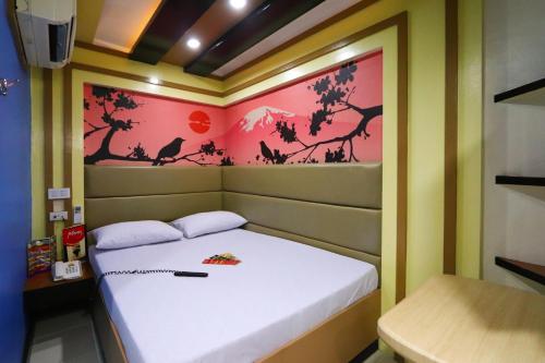 a small bedroom with a bed and a painting on the wall at Hotel Sogo Makati Avenue in Manila