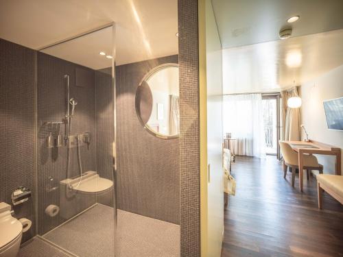 a bathroom with a shower with a toilet and a sink at Resort Hof Weissbad in Weissbad