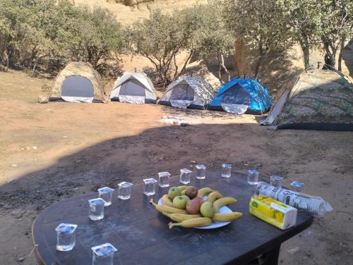 a table with bananas and glasses of water and tents at Dana Village experience hotel in Dana
