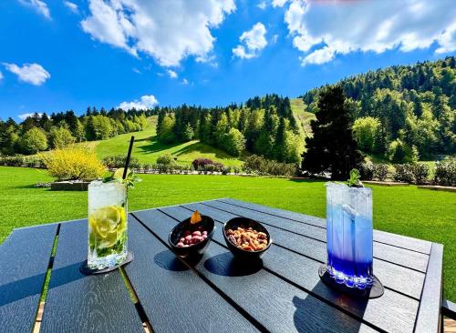 a picnic table with a bowl of food and two cocktails at Domaine de Montagne - Hôtel Chalet Frère Joseph in Ventron