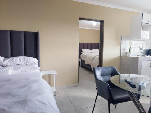 a bedroom with two beds and a table and a chair at Cosmo Sleepover in Roodepoort