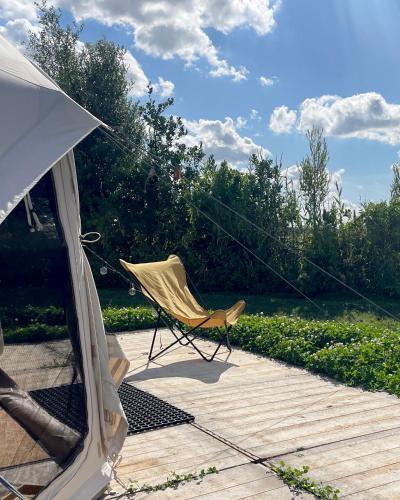 a chair sitting on a patio with a tent at Voedselbos Camping Koperwiek in Hazerswoude-Dorp