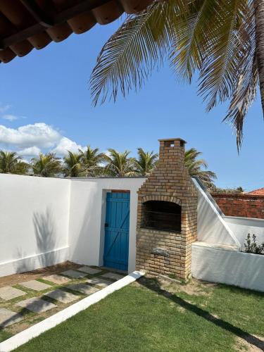 a house with a blue door and a brick fireplace at Villa Carlotta Praia Uruaú 5 camere da letto in Beberibe