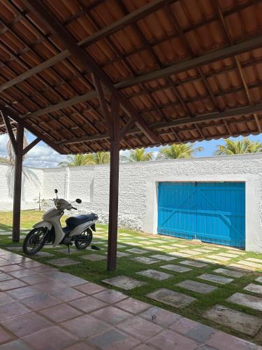 a motorcycle parked under a building with a blue garage at Villa Carlotta Praia Uruaú 5 camere da letto in Beberibe