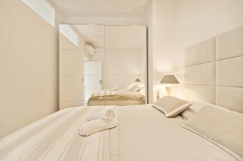 une chambre blanche avec un grand lit et un miroir dans l'établissement Modern Apartment - 1BD 4P - Center of St Tropez, à Saint-Tropez