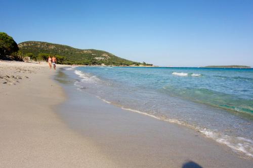 two people walking on a beach near the water at Résidence Belvedere de Palombaggia in Porto-Vecchio