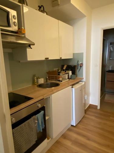 une cuisine avec des armoires blanches et un évier dans l'établissement Studio Nice Prom', à Nice