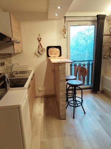 une cuisine avec un comptoir et deux tabourets et un balcon dans l'établissement A cocoon in Les 2 Alpes, à Les Deux Alpes