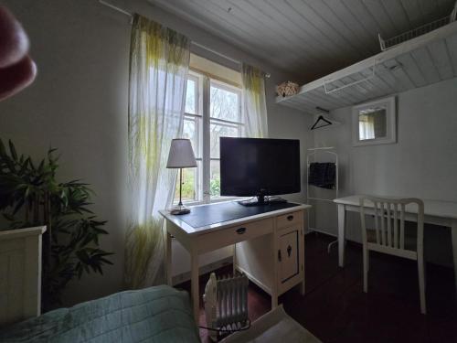 a living room with a desk with a television on it at Private room in a 250 years old house in Helsinki