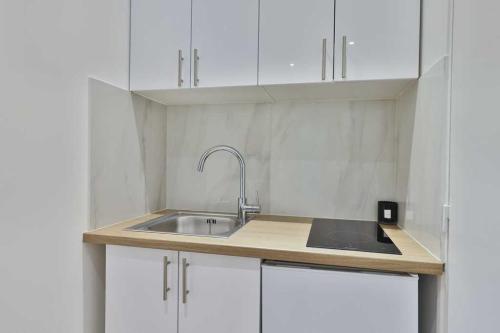 - une cuisine avec un évier et des placards blancs dans l'établissement Close to Marais l 20min from Louvre by transport, à Paris