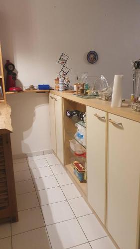 Il comprend une cuisine avec des placards blancs et du carrelage blanc. dans l'établissement L'Opale - Chez L'habitant, à Château-du-Loir