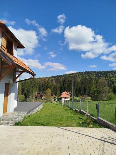 a building with a fence and a grass field at Tara Mountain House in Bajina Bašta