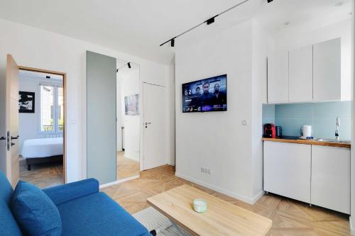 un salon avec un canapé bleu et une cuisine dans l'établissement Charming Appt - 1BDR 4P - Saint Ouen, à Saint-Ouen