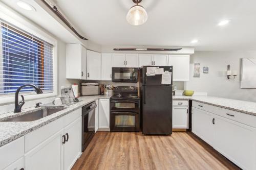 una cucina con mobili bianchi e un frigorifero nero di Hedges 7J - Comfortable Mountain Retreat a North Creek