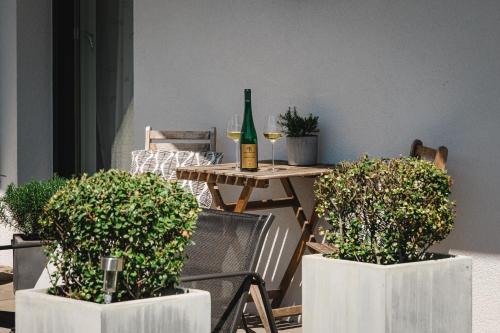 a table with a bottle of wine and two potted plants at Wachaulodge in Weissenkirchen in der Wachau