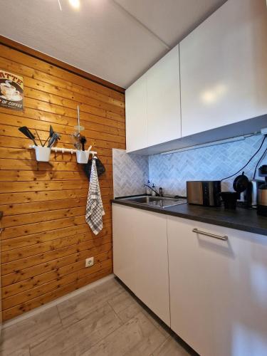 a kitchen with white cabinets and a wooden wall at Schwarzwald Pur in Sasbachwalden