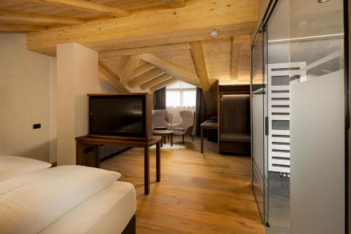 a room with a bed and a television and a table at Camino Rustic Chic Hotel in Livigno
