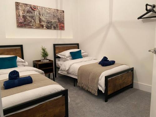 a bedroom with two beds with blue pillows on them at Bright & Cosy Retreat in Swansea in Swansea