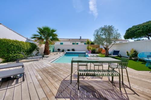 un patio avec une table et des chaises et une piscine dans l'établissement Villa pour 8 avec piscine à La Flotte en Ré, à La Flotte
