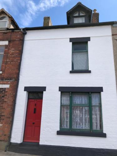 a white building with red doors and windows at Phoenix Nights Guest House in Barrow in Furness