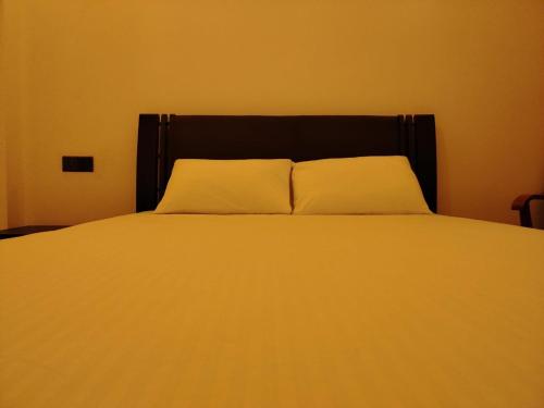 a bed with a black headboard and two white pillows at Diora Hotel in Ratnapura