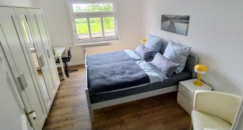 a bedroom with a bed and a window and a chair at Steinaublick Ferienwohnung - Schnell in Hamburg-Lübeck-Lüneburg-Schwerin-Ostsee in Büchen