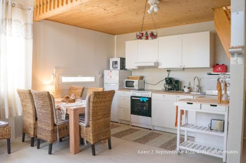 a kitchen with a table and chairs and a kitchen with white cabinets at Villa Repovesi in Hillosensalmi