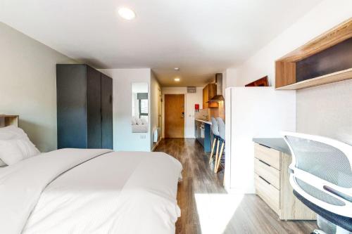 a bedroom with a white bed and a kitchen at Canvas Glasgow - in City Centre in Glasgow