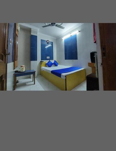 a bedroom with a bed with blue sheets and a table at Hotel Simla Inn in Lucknow