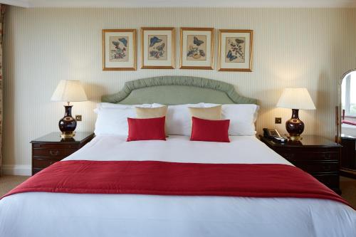 a bedroom with a large white bed with red pillows at Cheval Thorney Court at Hyde Park in London
