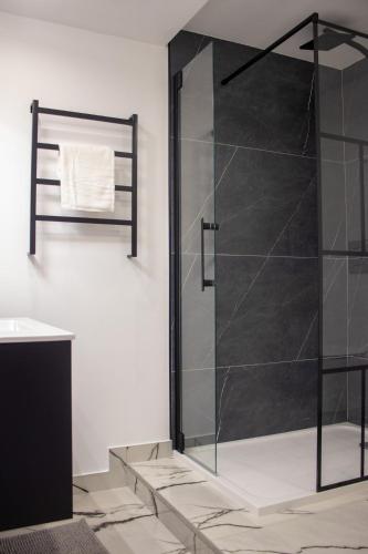 une douche avec une porte vitrée dans une salle de bain dans l'établissement Suite George - 4 pers proche du coeur historique, à Charleville-Mézières