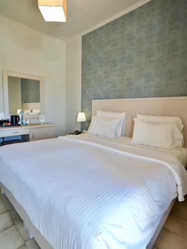 a large white bed with white sheets and pillows at Telesilla Hotel in Kontokali