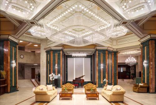 a large lobby with couches and a chandelier at Natsionalny Hotel in Kyiv