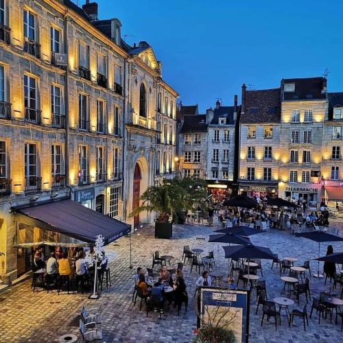 Un groupe de personnes assises à des tables dans une rue avec des bâtiments dans l'établissement Appartement de charme hyper centre ville de Caen, à Caen