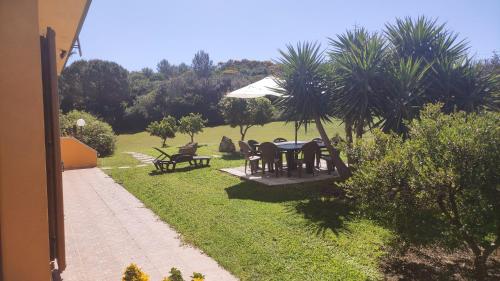 a garden with a table and chairs and an umbrella at Grotta Delle Fate in Ossi