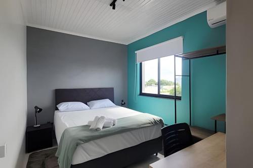 a bedroom with a bed with blue walls and a window at AP102 - Apartamento com AC no centro in São Miguel dʼOeste