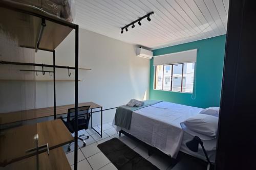 a bedroom with a bed and a desk and a window at AP104 - Amplo AP no centro c/ AC in São Miguel dʼOeste