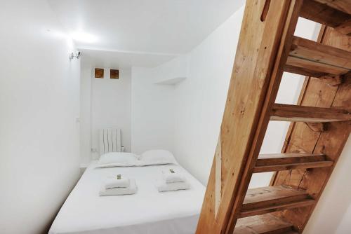 Cette chambre comprend un lit et une échelle en bois. dans l'établissement Souplex l 20 minutes by metro from Opéra Garnier, à Paris