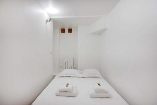 - une chambre blanche avec un lit et 2 serviettes dans l'établissement Souplex l 20 minutes by metro from Opéra Garnier, à Paris