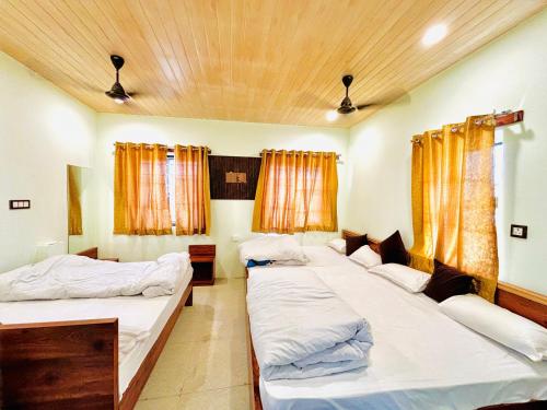 a room with three beds and two windows at Hotel Khushhal Manzil in Ajmer