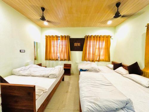 three beds in a room with orange curtains at Hotel Khushhal Manzil in Ajmer