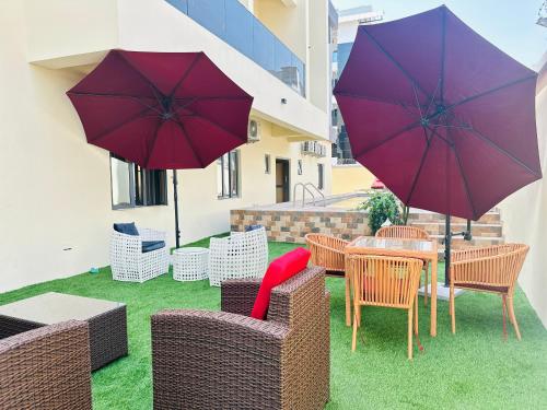 un patio con sillas y mesas con sombrillas en Gemmes Apartment, en Lekki