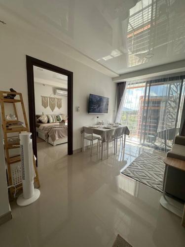 a living room with a table and a bedroom at Boho Apartment in Mai Khao Beach