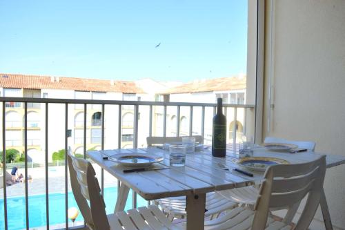 - une table en bois avec une bouteille de vin sur le balcon dans l'établissement NP170-C068 Appartement 2 pièces mezzanine, Narbonne Plage, à Narbonne-Plage