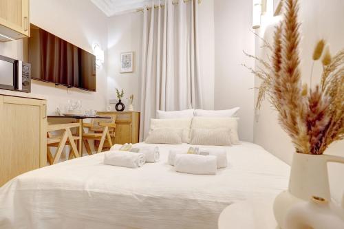 - une chambre blanche avec un grand lit blanc et des oreillers blancs dans l'établissement Studio luxueux a Paris with AC a proximite du Marais, à Paris