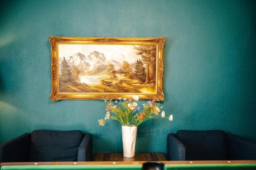 a painting on a blue wall with a vase of flowers on a table at WagnerStays BadEms Historic VillaWhirpool Billiard in Bad Ems