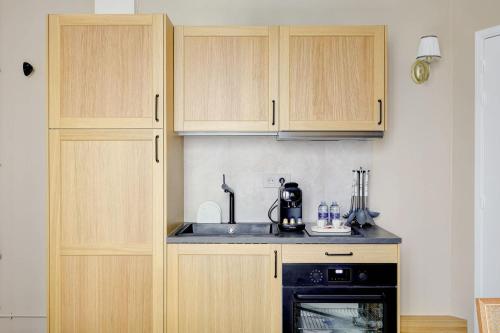 une cuisine avec des armoires en bois, un évier et une cuisinière dans l'établissement Appartment haut de gamme en plein coeur de Paris, à Paris