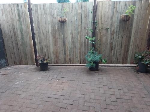 a patio with potted plants and a fence at Tevrede Guest Cottage in Bloemfontein
