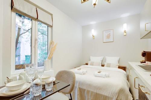 une chambre blanche avec un lit et une table dans l'établissement Charming studio with A-C, à Paris